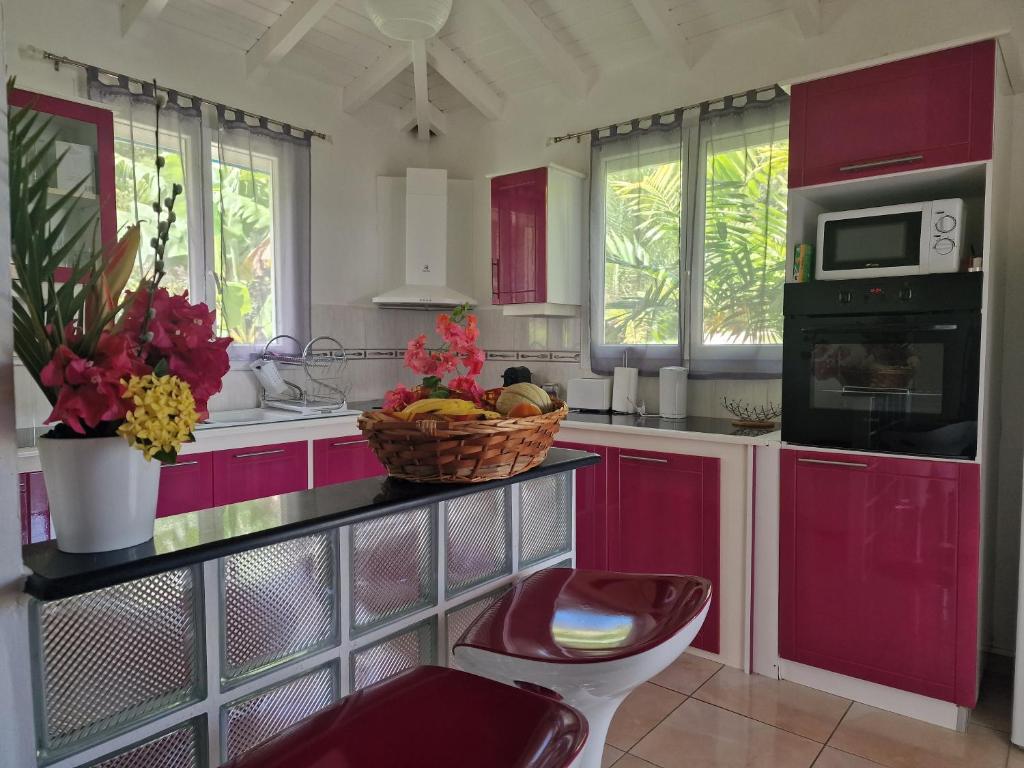 勒穆莱Les Villas de Boisvin的厨房配有红色橱柜和一篮水果的柜台