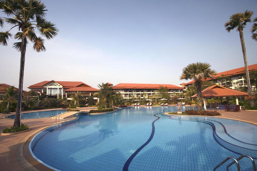 暹粒暹粒花园皇宫度假村的一座棕榈树和建筑的大型游泳池