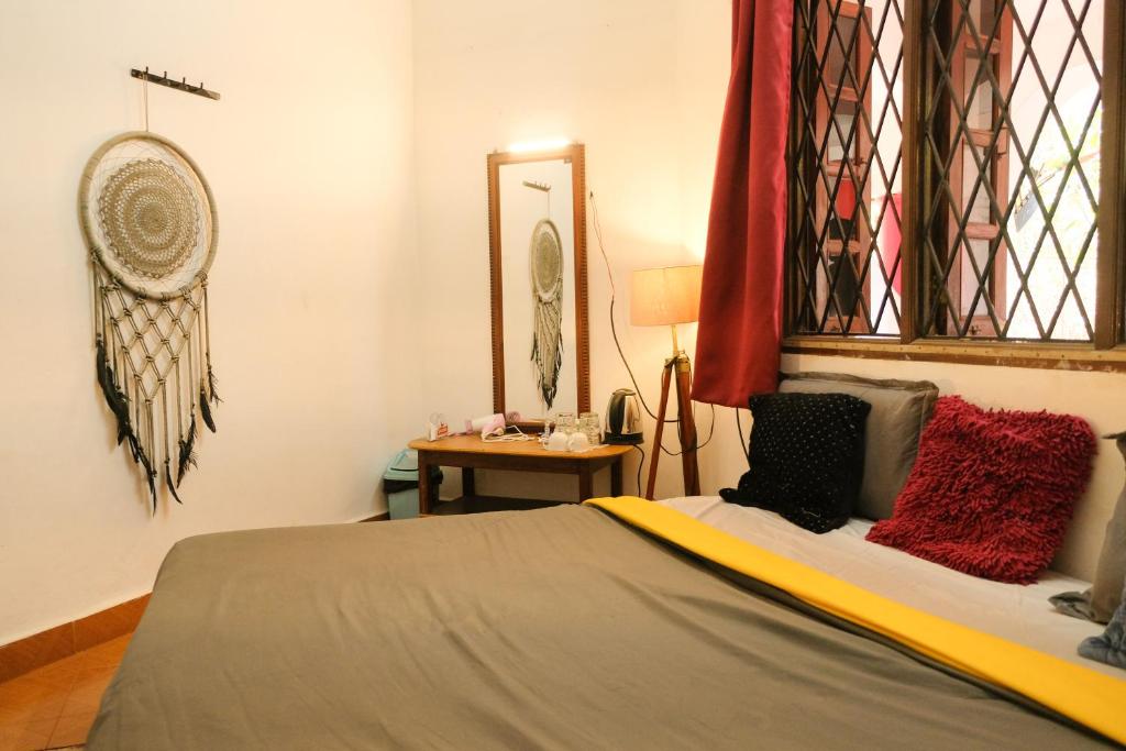 瓦加托Mitra Hostel Vagator的一间卧室配有一张带红色枕头和镜子的床