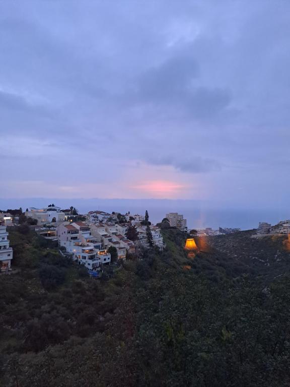 海法Sea view Carmel Mountain University的山丘上一群有日落的建筑