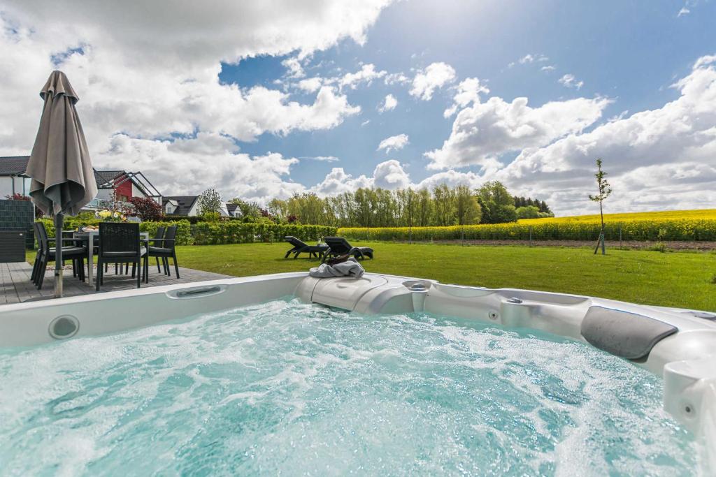 格赫伦-莱宾Luxus_Ferien_VILLA AMICI的庭院内的热水浴池配有桌子和遮阳伞