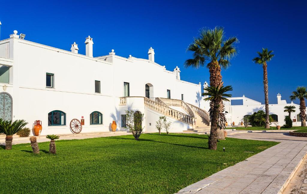 佩兹迪格雷科马塞里亚瑞莱斯卡尔迪纳莱酒店的一座白色的建筑,前面有棕榈树