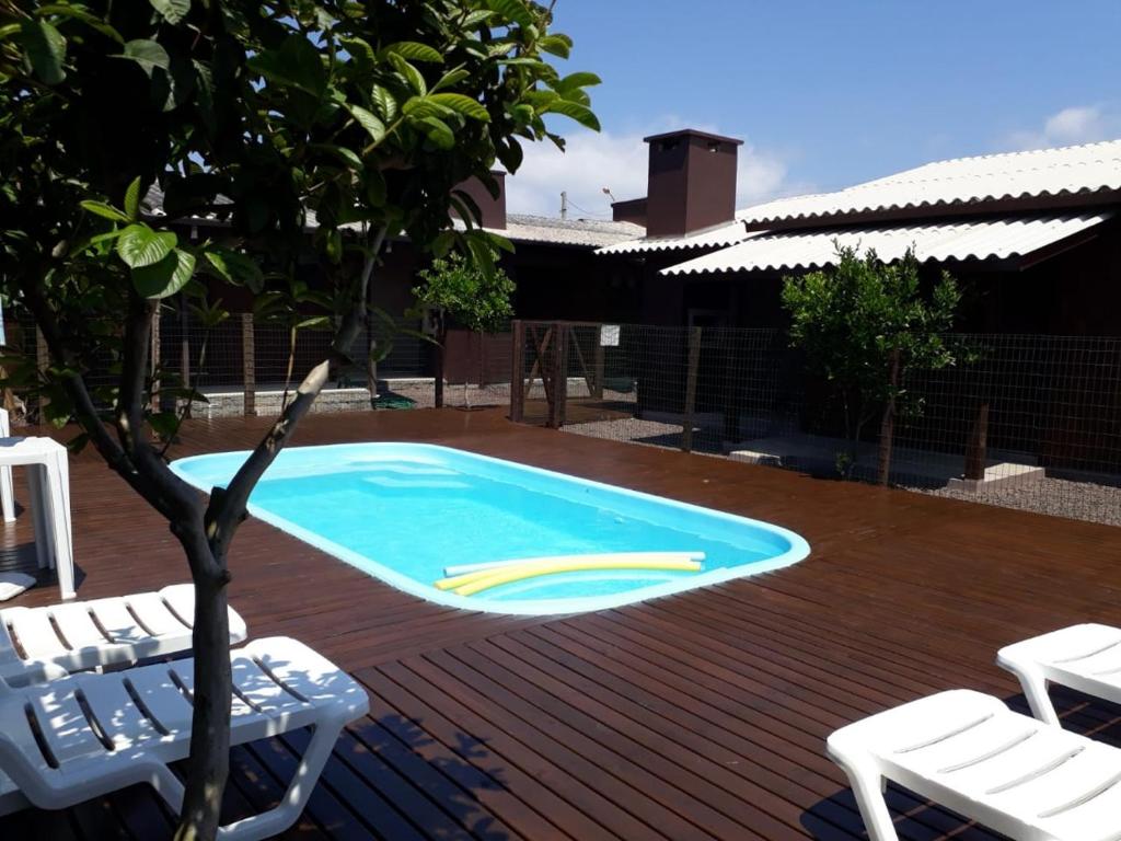 托雷斯Lindo Residencial na Praia Itapeva Torres的一个带两把草坪椅和一棵树的游泳池