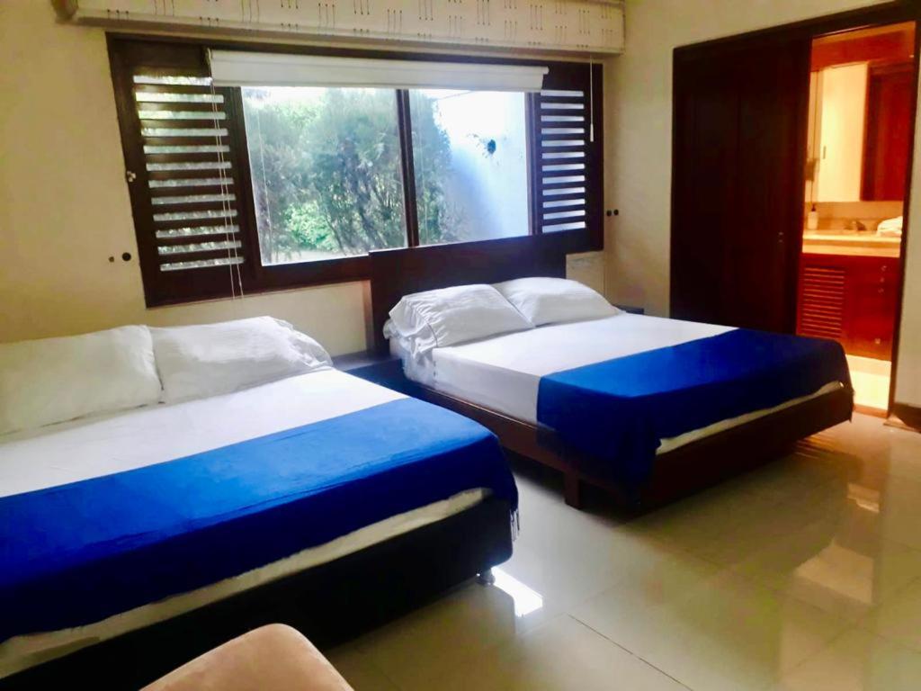 卡利Casa Jardin del Lago的一间卧室设有两张床和窗户。