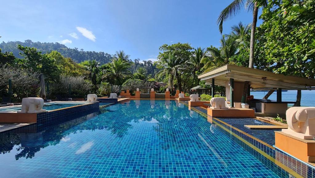 蔻立Baan Khaolak Beach Resort的一个带椅子的度假村的游泳池,以及大海