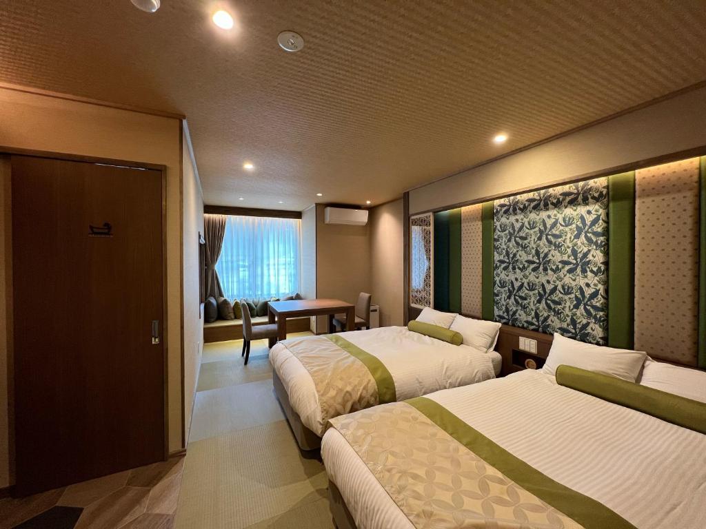 日光丸京日式旅馆的酒店客房设有两张床和一张桌子。