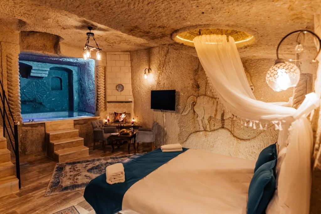 于尔居普Bayar Cave Suites的一间卧室配有一张带窗帘和桌子的床