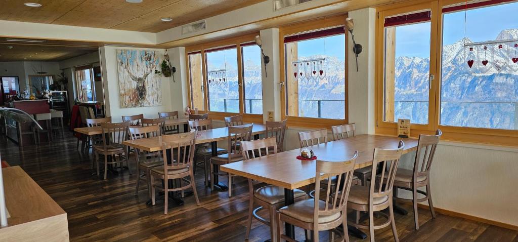 Flums斯霍恩哈顿贝格酒店的餐厅设有木桌、椅子和窗户。