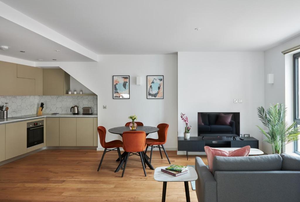 伦敦Hammersmith Mews by Viridian Apartments的厨房以及带桌椅的起居室。