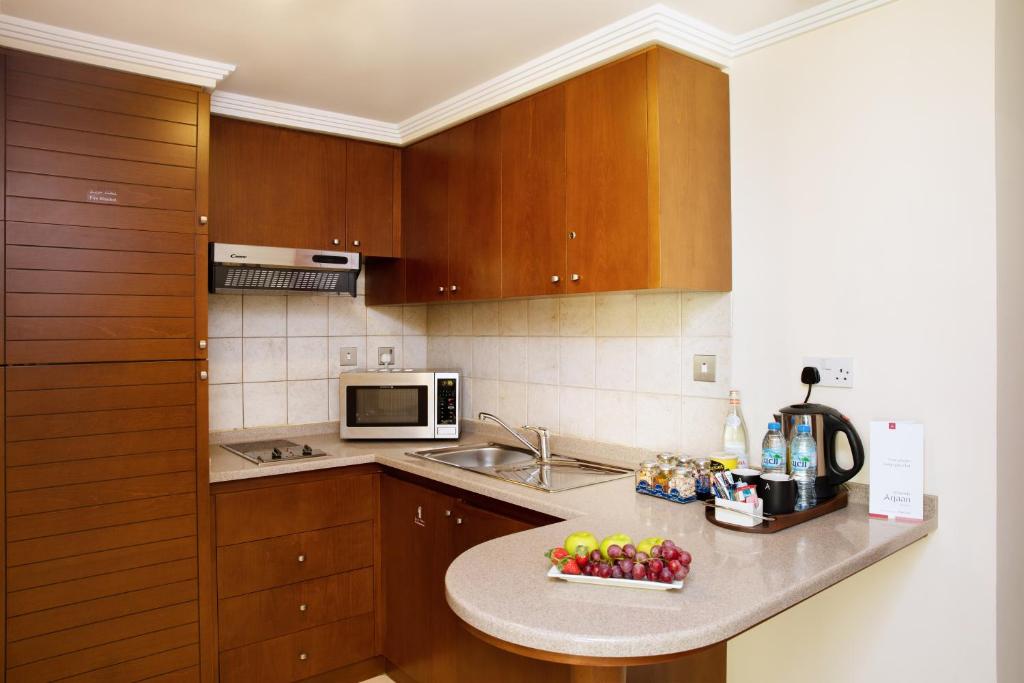 阿布扎比阿尔拉达阿亚罗塔纳阿布扎比酒店的厨房配有木制橱柜和柜台上的一碗水果