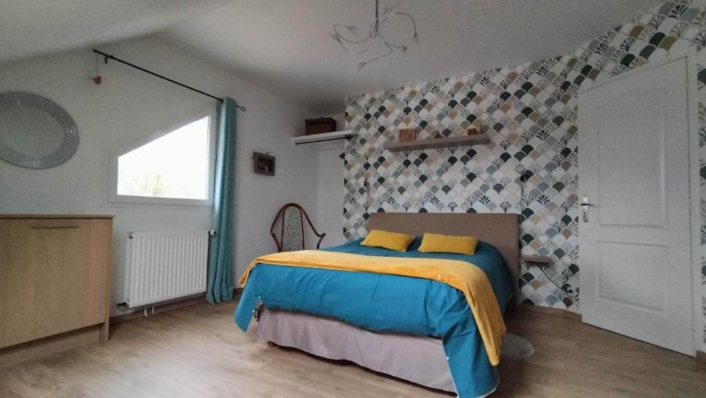 Glos-sur-RisleAppartement Vallée de la Risle的一间卧室配有一张黄色和蓝色毯子的床