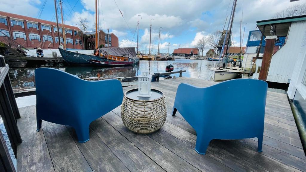 哈尔德韦克Woonboot 4 Harderwijk的码头上配有两把蓝色椅子和一张桌子,船坞上配有船只