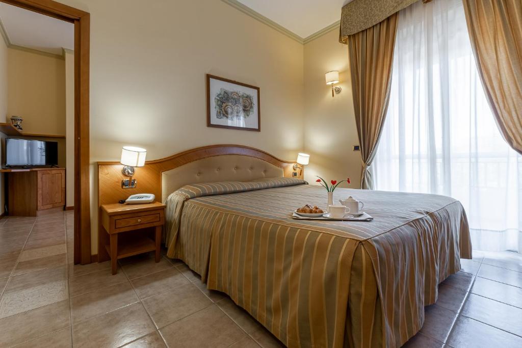 锡拉库扎休闲酒店的一间酒店客房,配有一张床铺,上面放着一个食物托盘