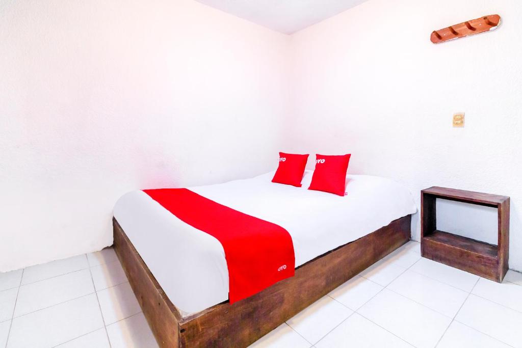 圣克里斯托瓦尔-德拉斯卡萨斯OYO Hotel La Luna的一间卧室配有一张带红色枕头的床和一张桌子
