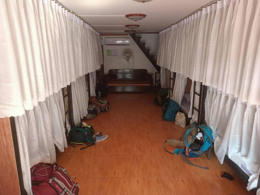 巴色Pakse Backpacker Hostel2023的一间设有走廊、白色窗帘和袋子的房间