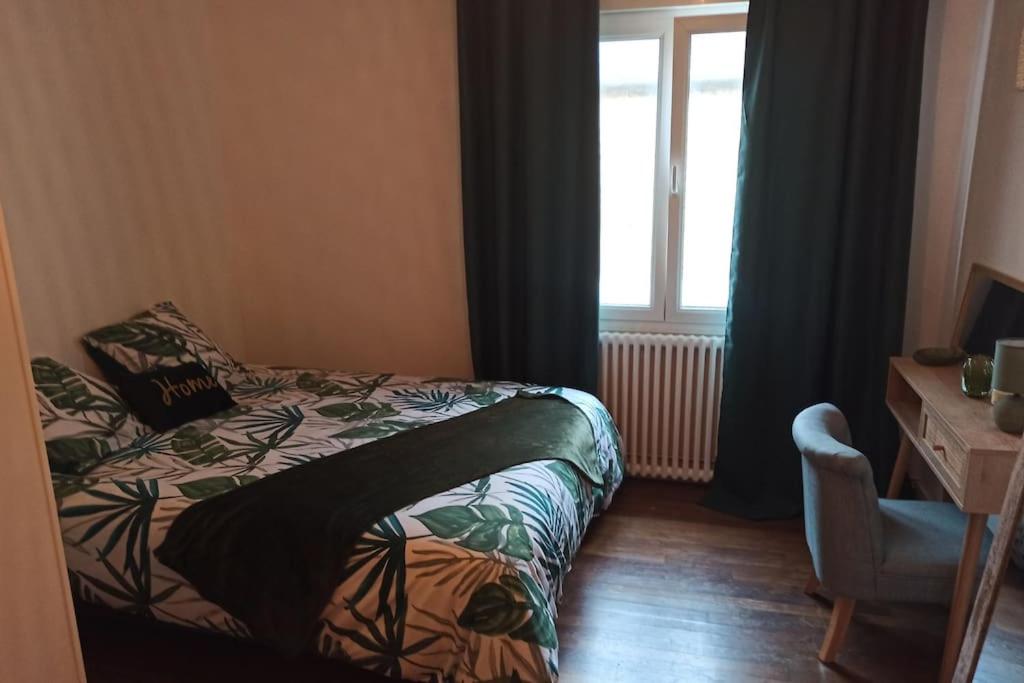 迪塞Petite maison de bourg proche A84的一间卧室配有一张床、一个窗口和一张书桌