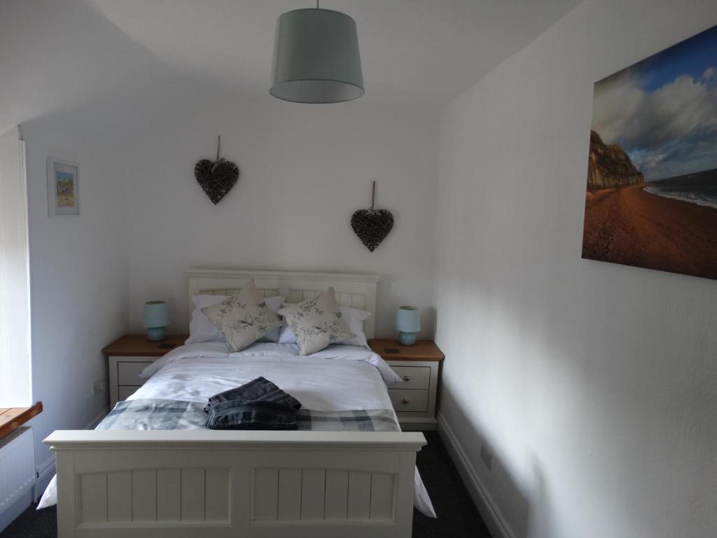布里德波特Staddlestones Cottage的卧室配有白色床,墙上有心