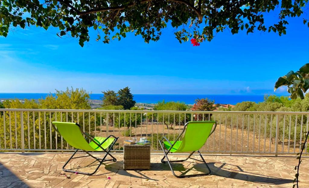 希克利Villa BeaBella的两把绿色椅子位于一个露台,后面是大海