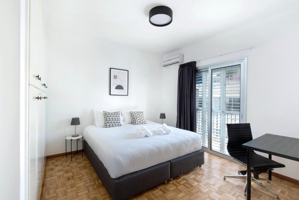尼科西亚Urban Condo 12 - 2 Bdr的白色的卧室设有床、书桌和窗户