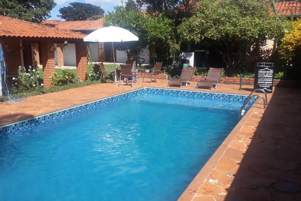 博伊图瓦Chácara Sossego do Vovô, Cond Vitassay - Boituva的蓝色游泳池配有椅子和遮阳伞
