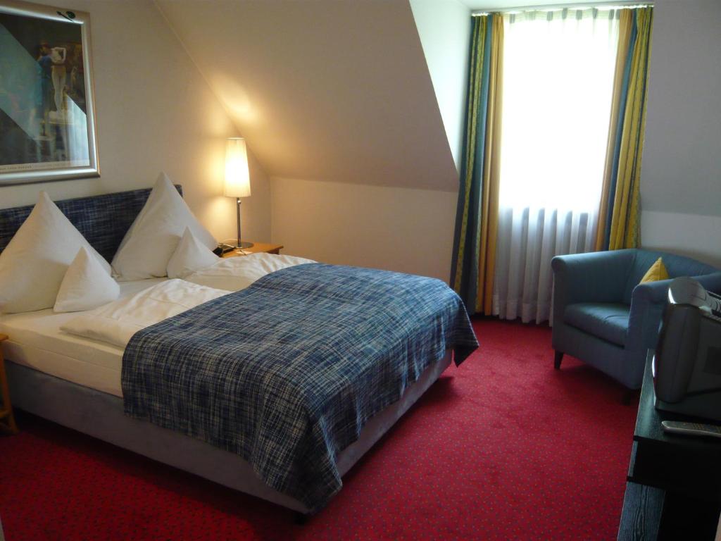 慕尼黑Hotel Nymphenburg City - München的配有一张床和一把椅子的酒店客房