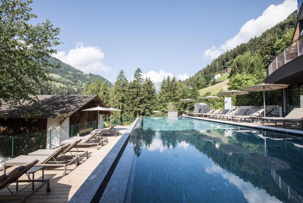 圣莱奥纳尔多因帕西里亚Hotel Bad Fallenbach的一个带躺椅的度假游泳池和一个山