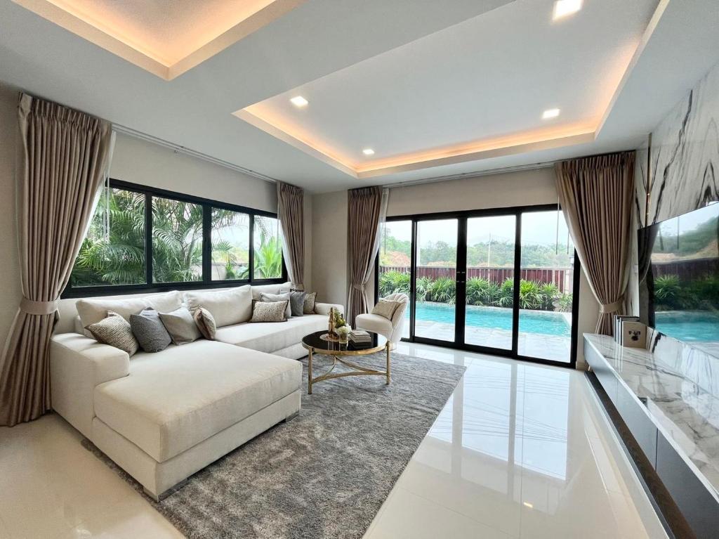 班怀雅Southern Peak Pool Villa Huay Yai Pattaya的客厅配有白色沙发和大窗户