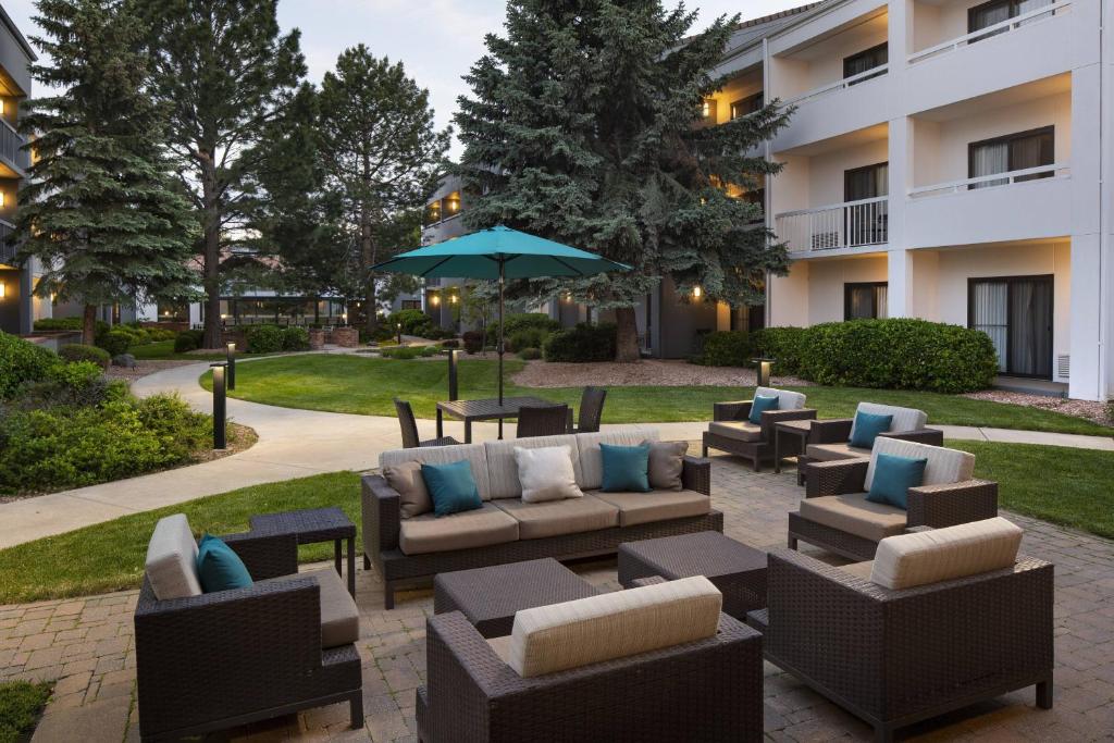博尔德博尔德万怡酒店的一个带沙发和桌子及遮阳伞的庭院
