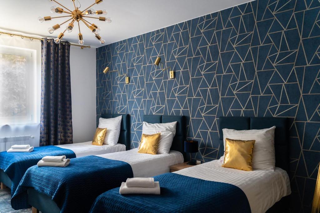 波兹南石楠膳宿公寓的蓝色和白色的客房内的三张床
