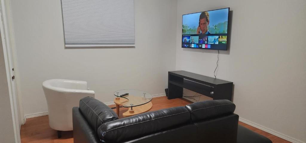 温尼伯ChessKings Guest House - Unit 1的客厅配有真皮沙发和平面电视