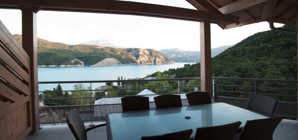 绍尔日Vue imprenable sur Lac de Serre-Ponçon à Chorges : appt prestige 8 pers的阳台配有桌椅,享有湖景