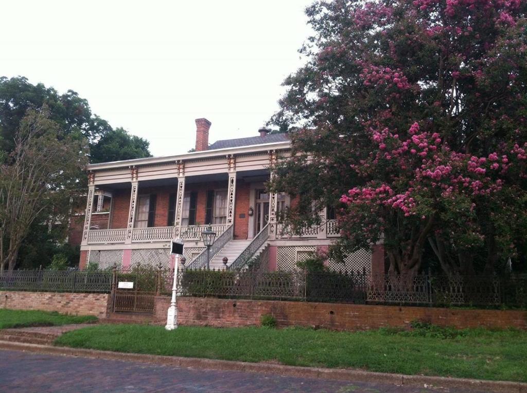 维克斯堡角落大厦住宿加早餐旅馆的一座带围栏的房子和一棵带粉红色花卉的树