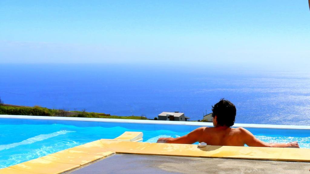 法亚·达·奥韦利亚Madeira Native Motion Guest House的坐在游泳池里看海洋的人