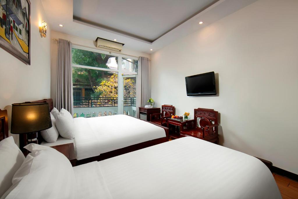 河内Hanoi Moonlight Hotel的酒店客房设有两张床和窗户。