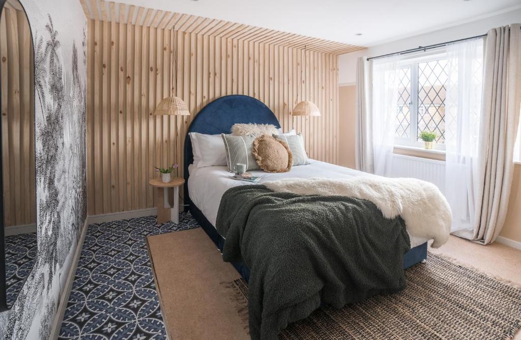 Churchdown4-bed Cotswold getaway with hot tub & gaming room的一间卧室配有一张带蓝色床头板的床和窗户