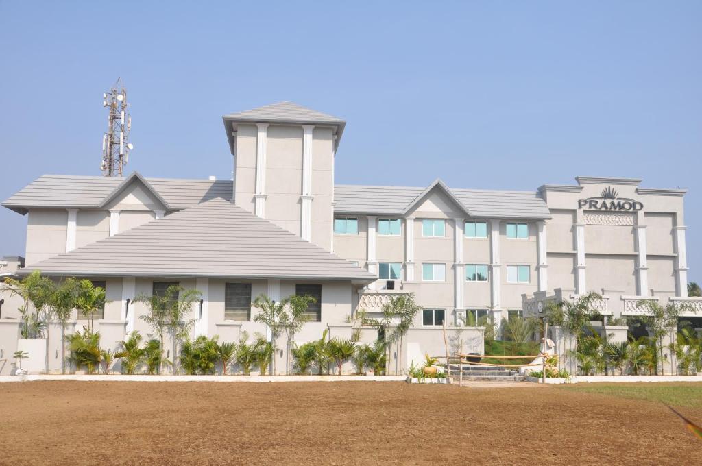 普里Pramod Convention & Beach Resorts的一座白色的大建筑,前面有棕榈树