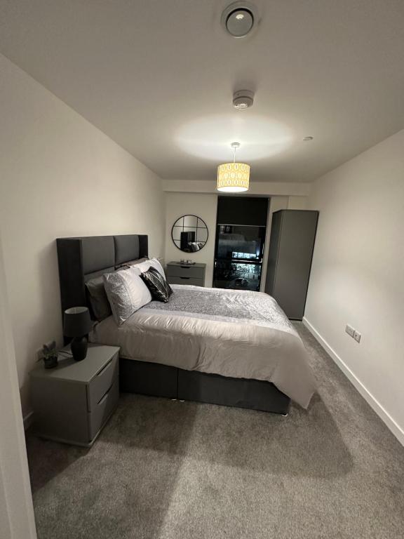 BroadheathManchester lovely two bedrooms apartment的一间卧室配有一张大床和一个床头柜