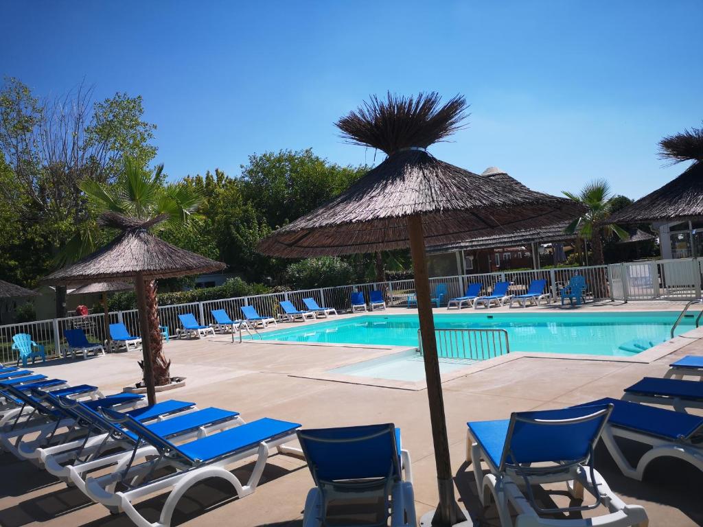 Lansargues乐夫都罗伊露营地假日公园的一个带蓝色椅子和遮阳伞的游泳池