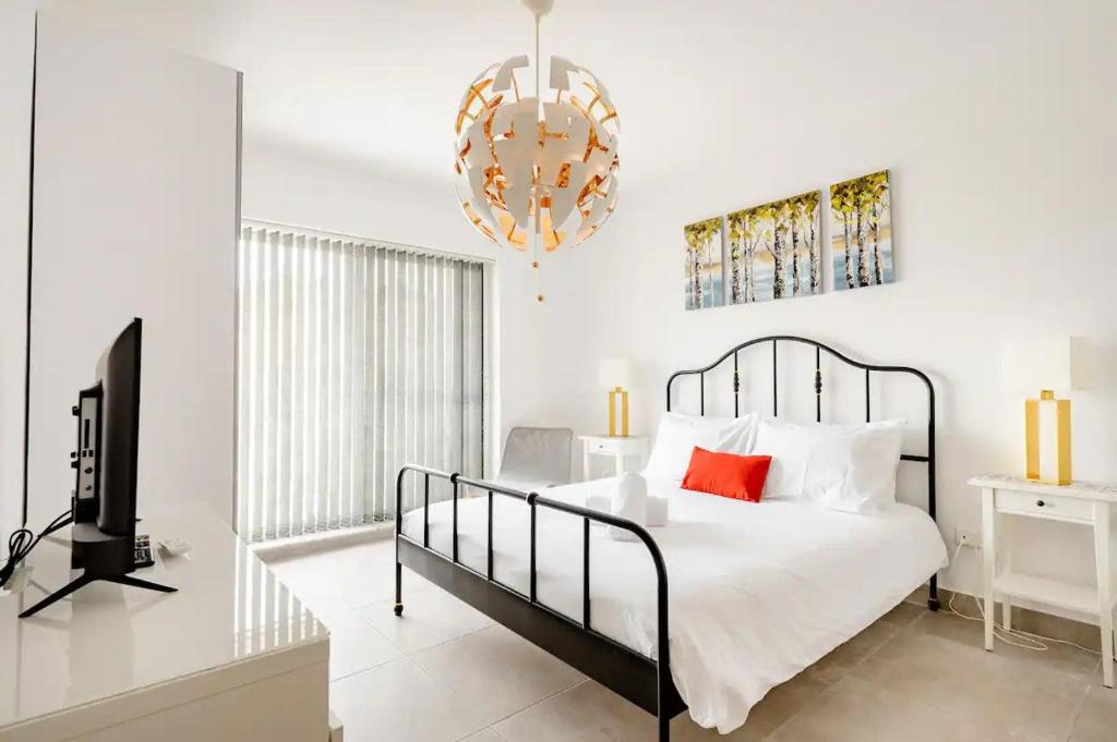 圣朱利安斯Casa Leon Malta的一间卧室配有一张床、一台电视和吊灯。