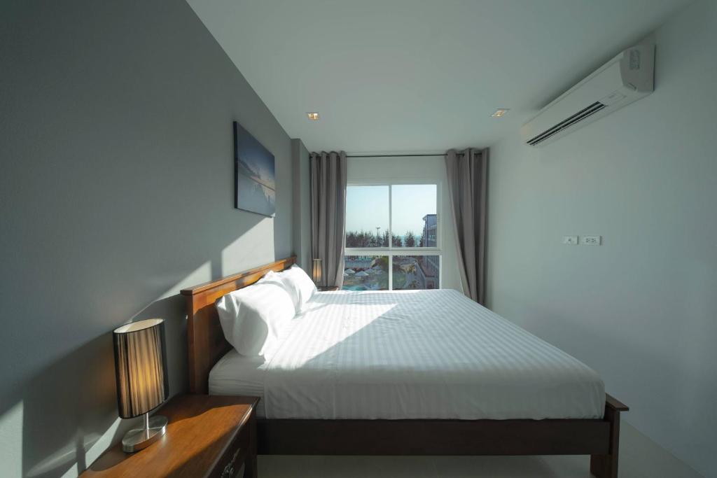 梅尔皮姆Mae Phim Grand Blue Condo 508 with pool and seaview的卧室配有白色的床和窗户。