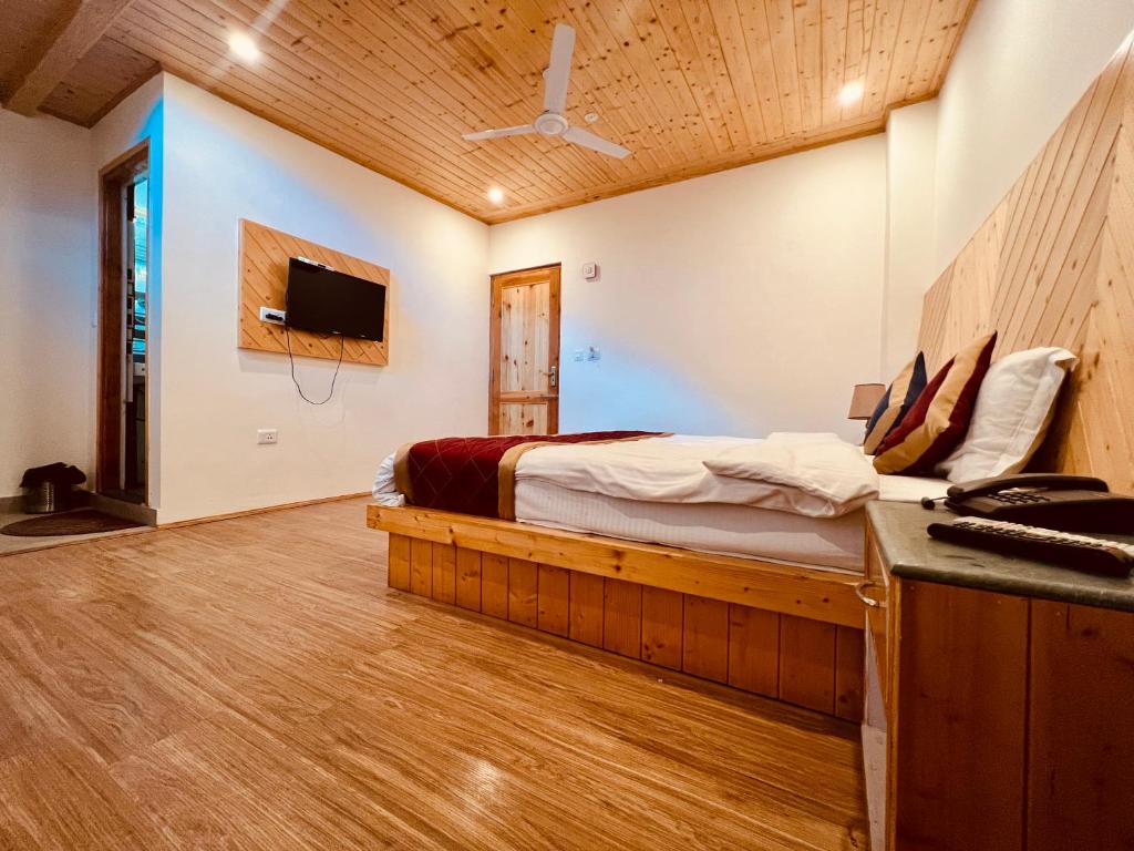 马拉里Hotel Radhika Manali的一间卧室配有一张床,墙上配有电视