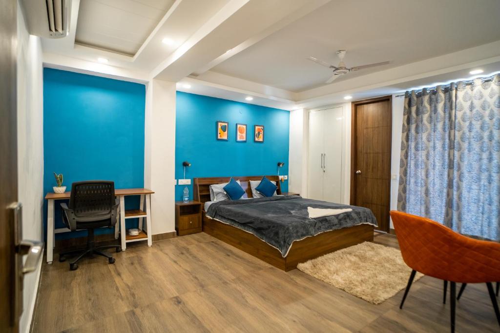 古尔冈FlxHo Uno - Serviced Apartment & Rooms - Golf Course Road的一间卧室设有蓝色的墙壁、一张床和一张书桌