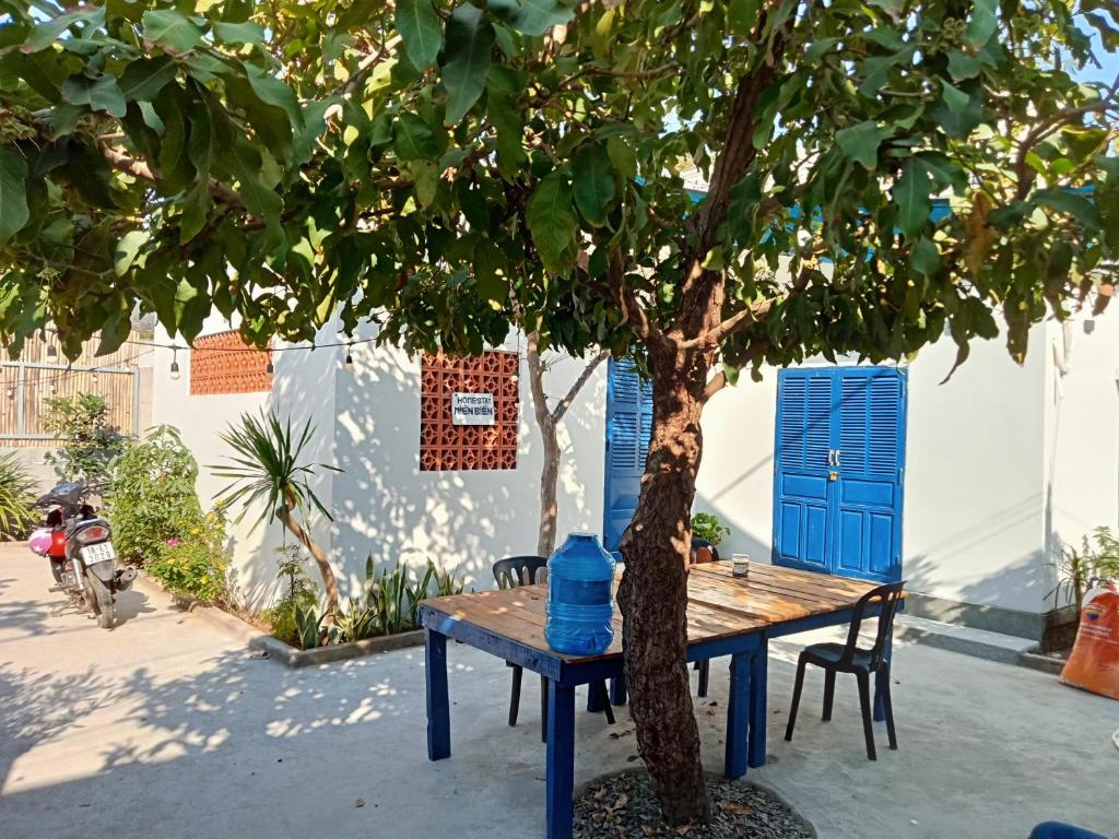 永熙Homestay Miền Biển Vĩnh Hy 2的树旁边的蓝色桌子,上面有蓝色的瓶子