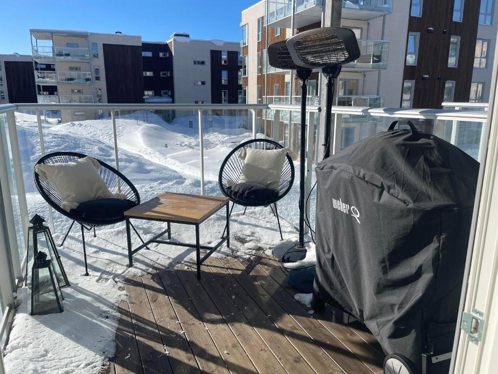 特罗姆瑟Leilighet sentralt i Tromsø的雪阳台配有两把椅子和一张桌子