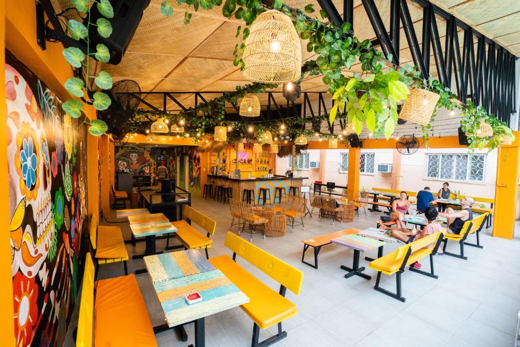 BulacaoNacho Hostel Cebu的餐厅设有黄色的桌椅,还有人坐在桌子旁