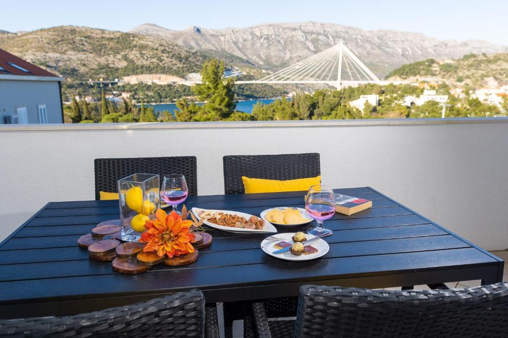 杜布罗夫尼克尔娜别墅酒店的阳台上配有带食物和酒杯的蓝色桌子