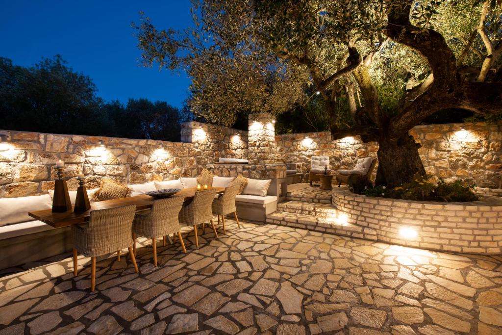 StavrosOlivea Premium Holiday Homes的天井配有桌椅和带灯的石墙