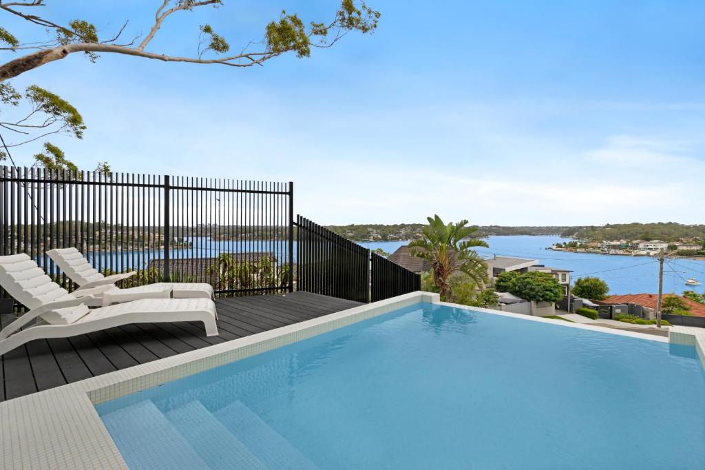 悉尼Luxury Waterside Home Sanctuary的游泳池位于带椅子和水的甲板上