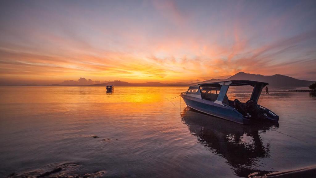美娜多Bunaken Sunrise Beach的日落时分坐在水中的船