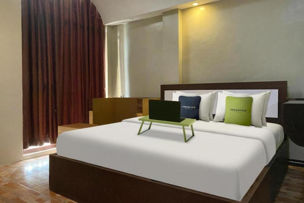 查亚普拉Urbanview Hotel Sabang Land Syariah Jayapura的一间卧室配有一张大床,上面有笔记本电脑